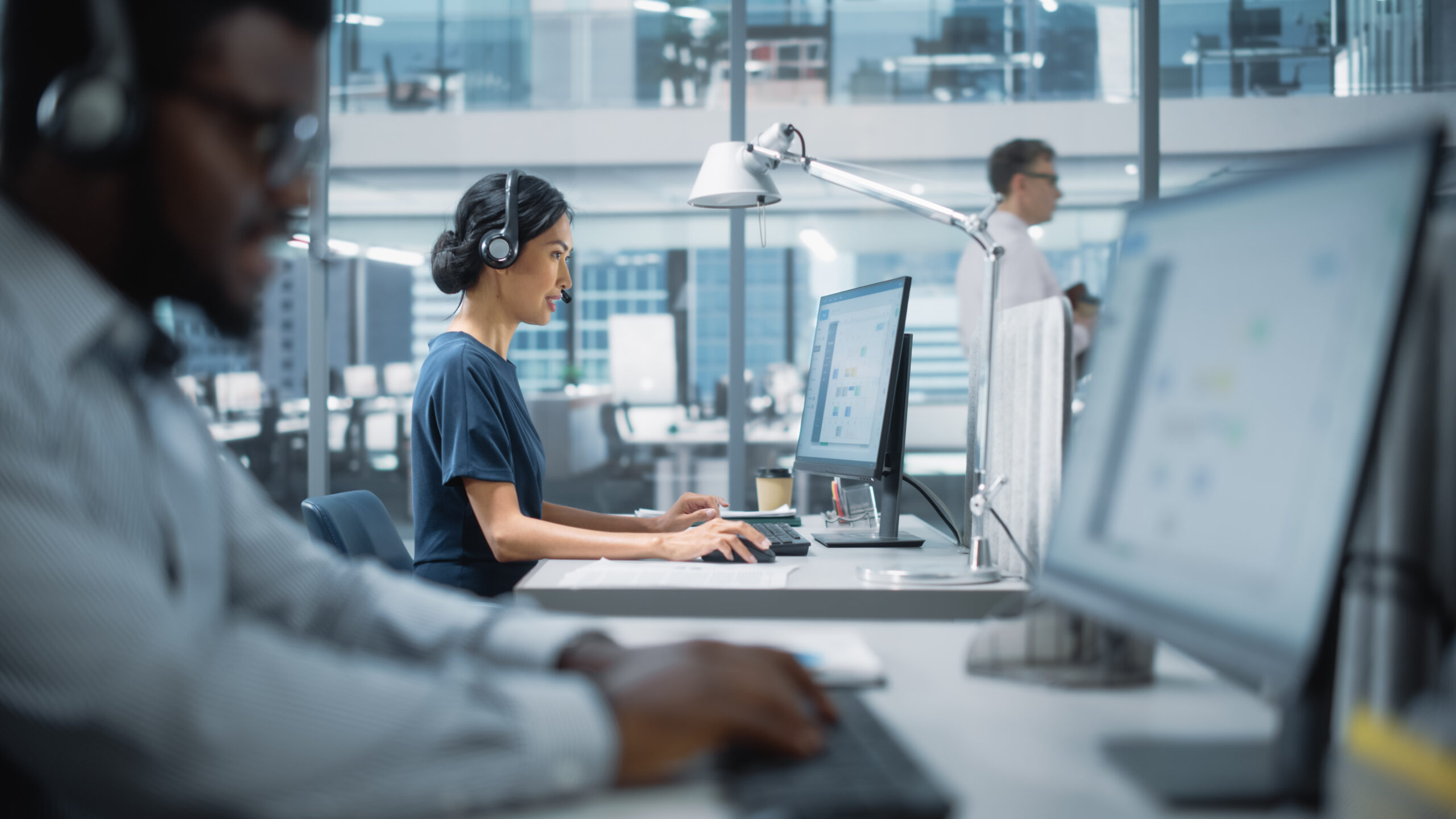 Professional Investment Traders Talking into Headset, Working on Computer with Screen Showing Finance Statistics, Charts Strategy, Stock Market, Telemarketing. Big Office Call Center.