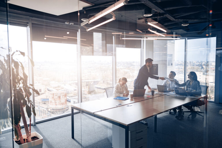 People standing near table, team of young businessmen working and communicating together in office